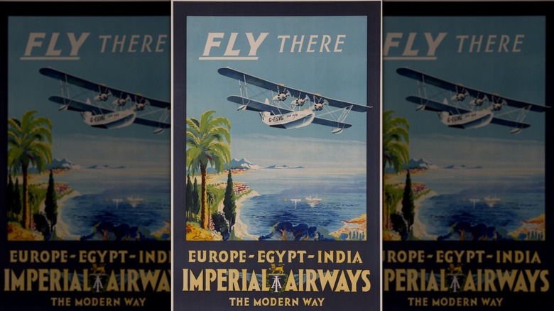 Close-up of vintage travel poster with "Fly There" written over a seaplane flying above palm trees