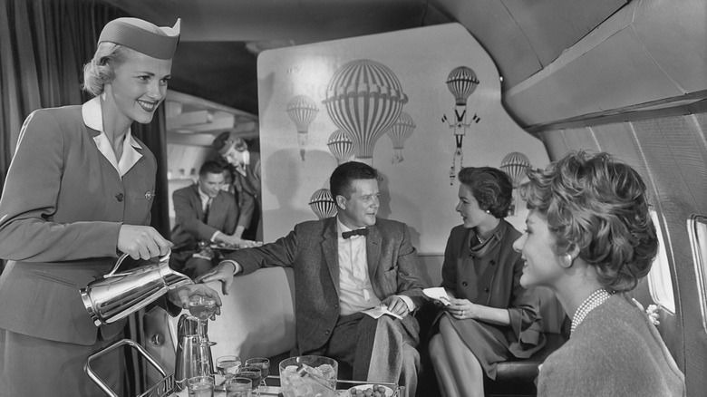 A flight attendant serves cocktails in the lounge of a new Pan American World Airways (Pan Am) Boeing 707, circa 1958.