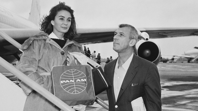British actress Jean Simmons (1929 - 2010) and her husband, screenwriter and director Richard Brooks (1912 - 1992) shows off a Pan Am flight bag while boarding a flight to Bangkok in Thailand, at London Airport (later Heathrow)