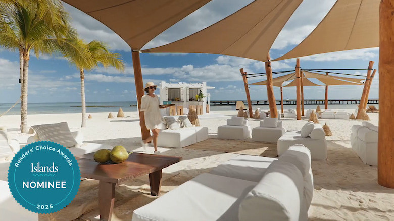 A woman carrying drinks through a beach lounge area at Etéreo, Auberge Resorts Collection