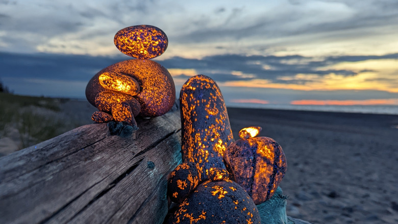 Glowing Yooperlite orange rocks against sandy beach