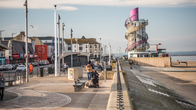 People on the beachfront promenade in Redcar, England, with the Redcar Beacon in the background.
