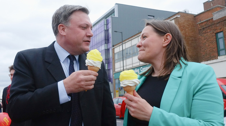 A man and woman in suits holding two famous lemon top ice creams in Redcar, England.