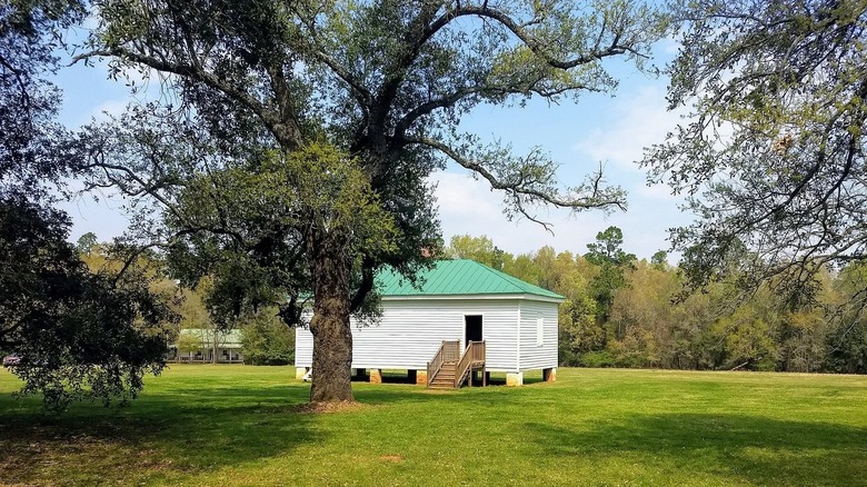 small white building in a field surrounded by trees