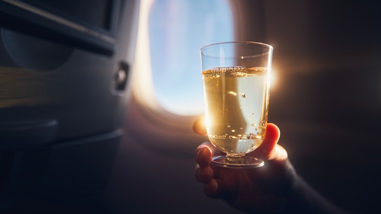 Person holding a glass of champagne inside a plane