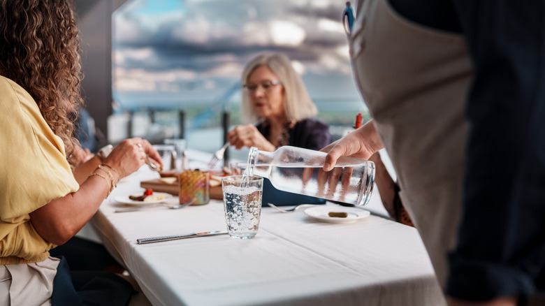 Someone pouring water for diners at a table
