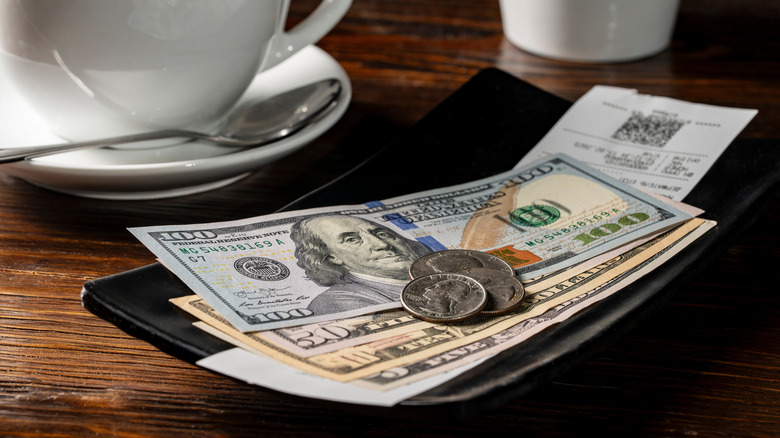 American money in a tip tray on a table with a coffee cup