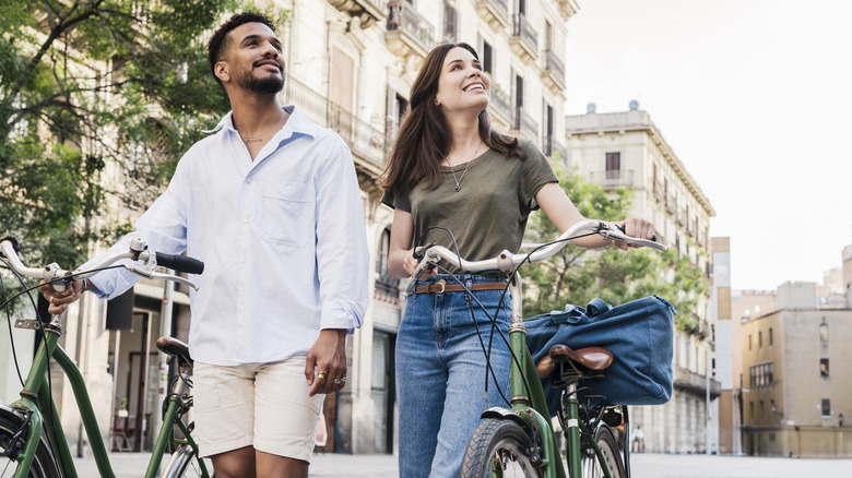 Couple walking their bikes on a street in Barcelona