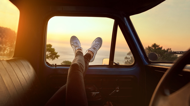 A woman's legs poke out of a car during a road trip