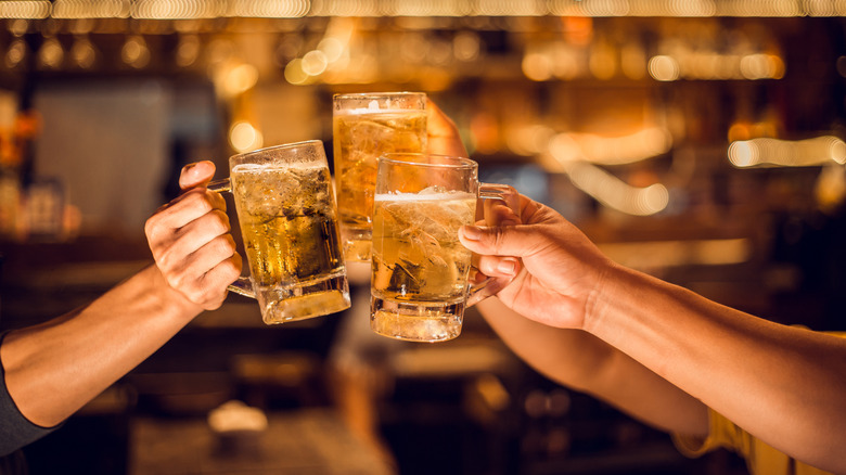 People toasting with raised beer mugs