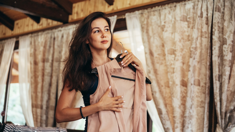 Woman holding a beige top up to her chest