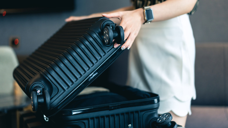 Woman opening a suitcase in a hotel room