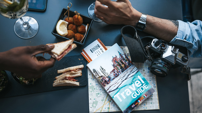 travel guidebook on a restaurant table with  food, maps, and a camera