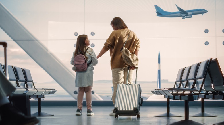Mother and daughter in airport watching planes