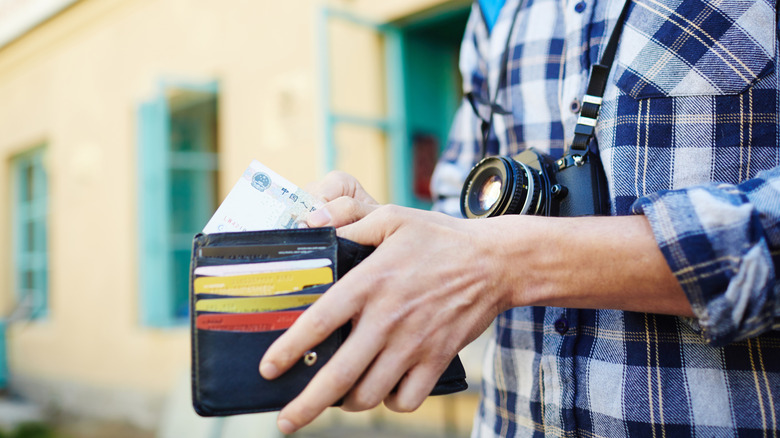 Young tourist putting money in their wallet
