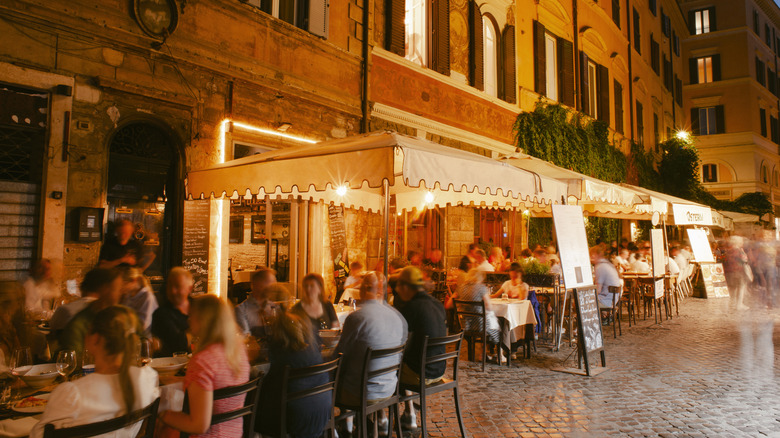 Diners sitting outside a restaurant in Rome at night