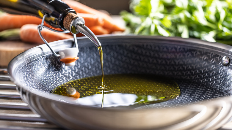 Hand pouring olive oil into a pan