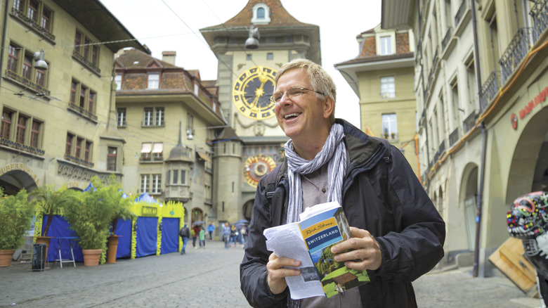 Rick Steves, American travel expert, conducting guidebook research in Bern, Switzerland, while holding a copy of "Rick Steves' Switzerland."