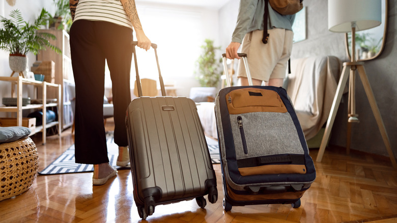 Two people holding their suitcases and walking into an accommodation