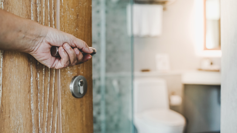 Person opening door to toilet