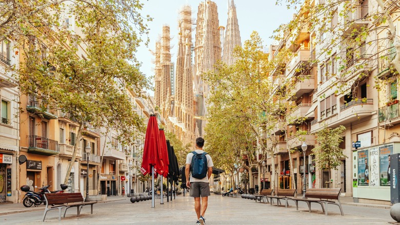 Man walking in shorts in front of the Sagrada Familia in Barcelona.