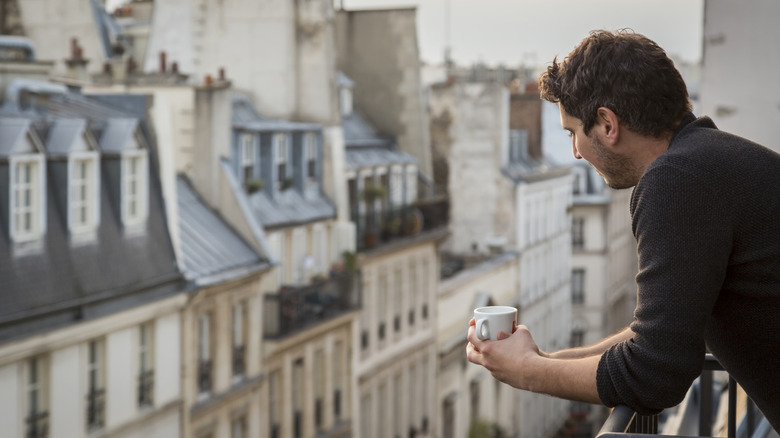 A man on the balcony of a Paris apartment