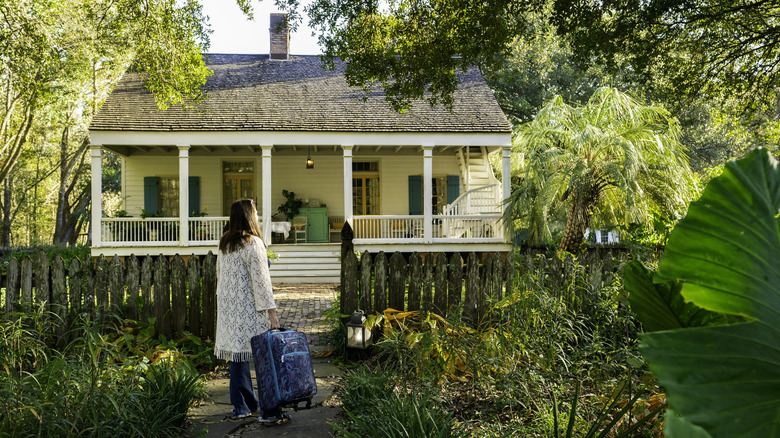 A guest standing in front of a B&B carrying luggage