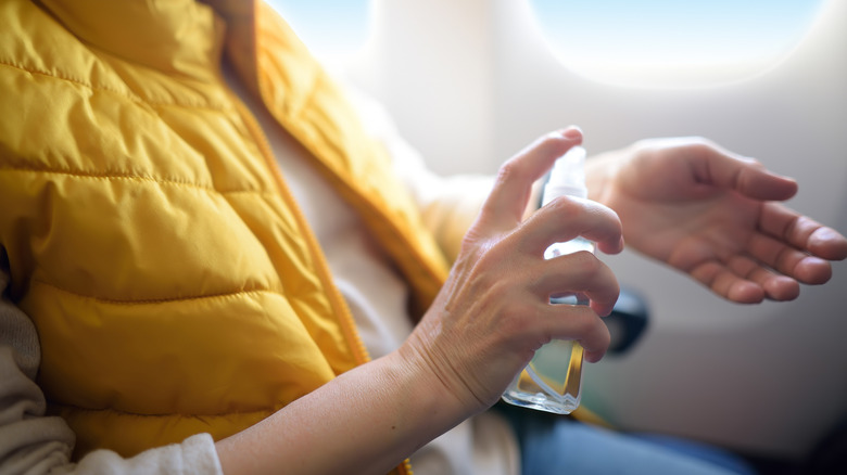 Person spraying hand disinfectant on airplane