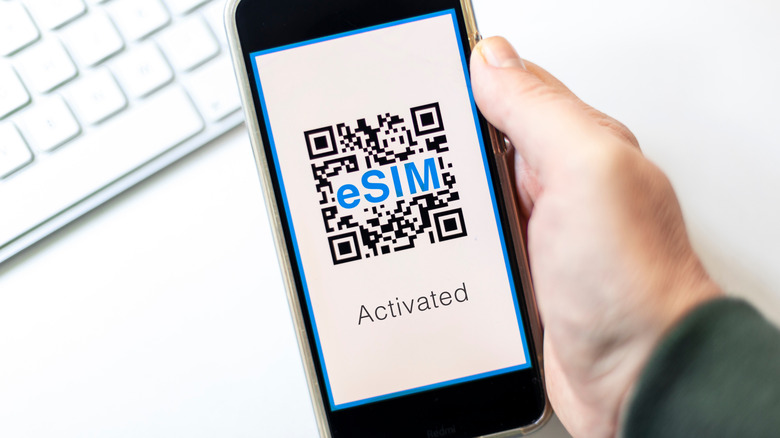 Hand holds cell phone open to eSIM QR code