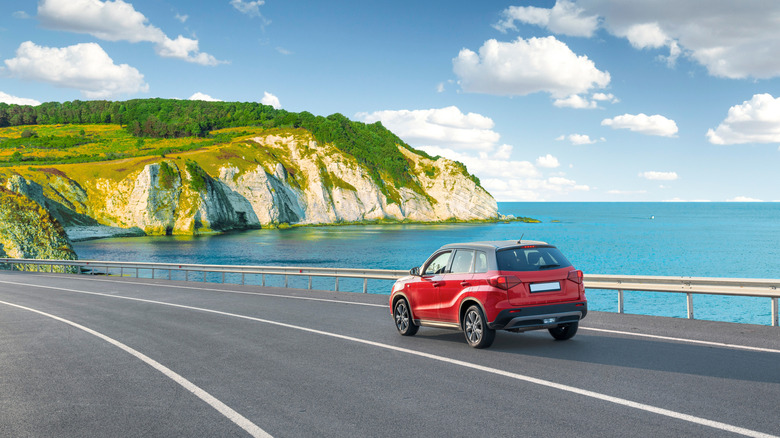 Red car driving on road near ocean