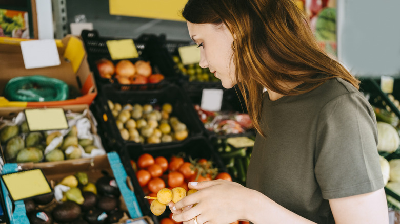 Woman buying produce with fruit in her hands