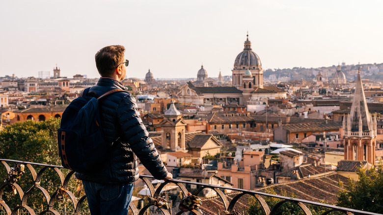 Traveler wearing a jacket looking out at Rome's skyline