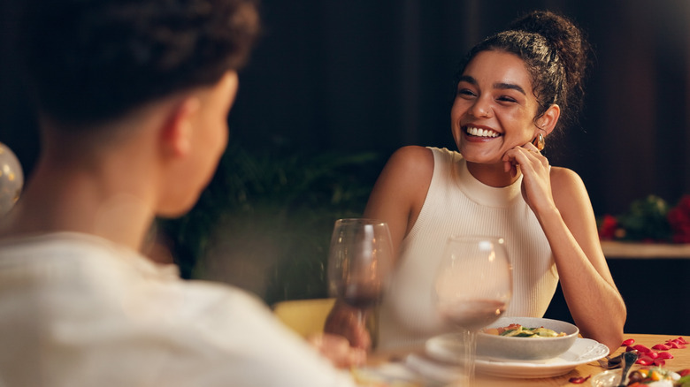 Woman smiling across the dining table with glass of wine
