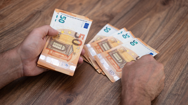 Two hands count out a pile of 50-euro cash notes