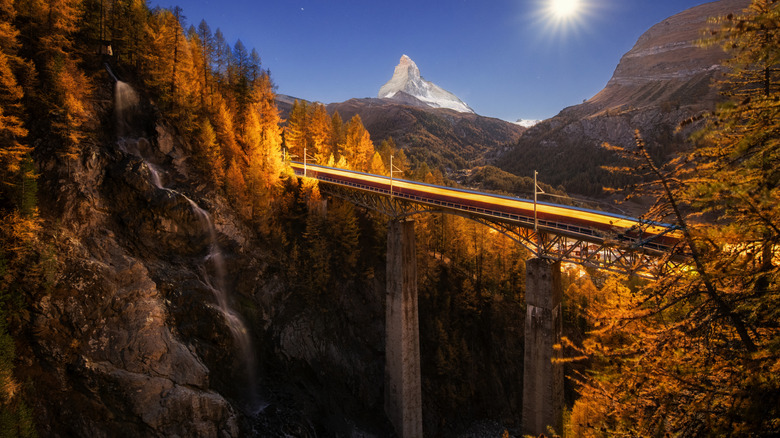 Train crossing a bridge in Switzerland at night during autumn