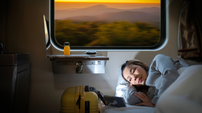 Woman on a sleeper train with a sunset out of her window