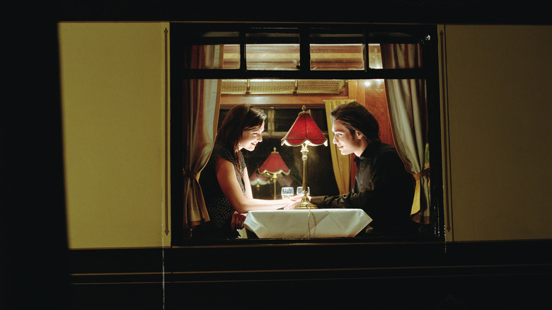 A couple in the window of a train dining car at night
