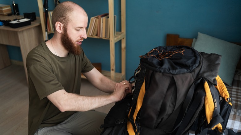 Man opening an internal-frame backpack