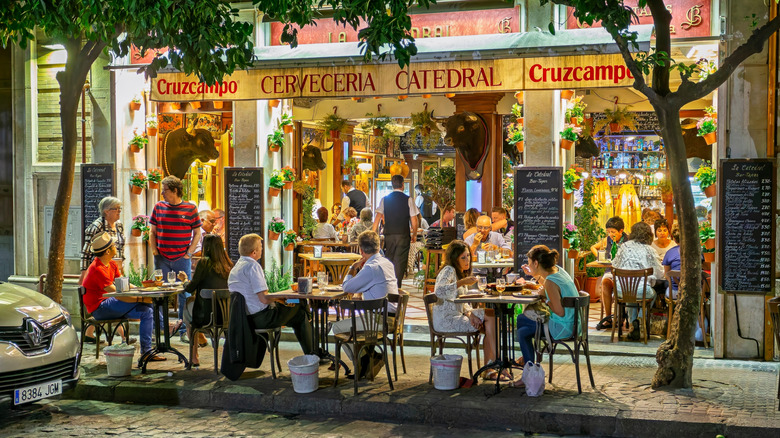 People sit outside a tapas bar in Seville, Spain
