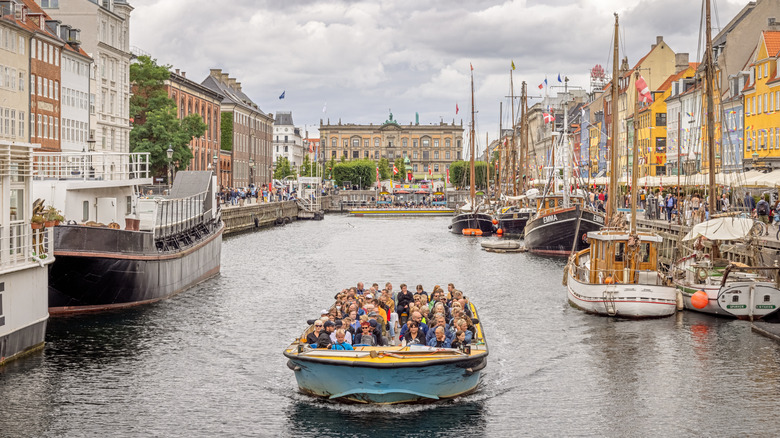 Boat full of people cruises down the canal of Nyhavn in Copenhagen, Denmark