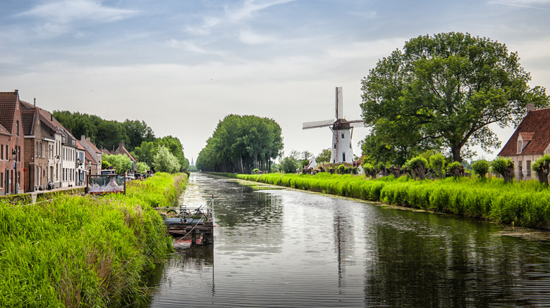 Canal near Damme, Belgium, lined with a traditional windmill and historic brick buildings