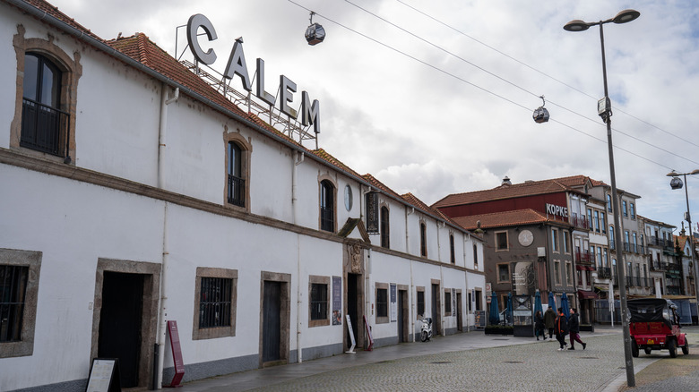 Signs reading "Calem" and "Kopke" stand above historic port wine caves in Gaia, where a cablecar carries passengers overhead