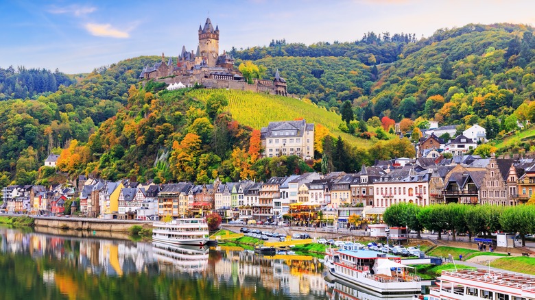 Castle on a hill overlooking a riverside town with boats