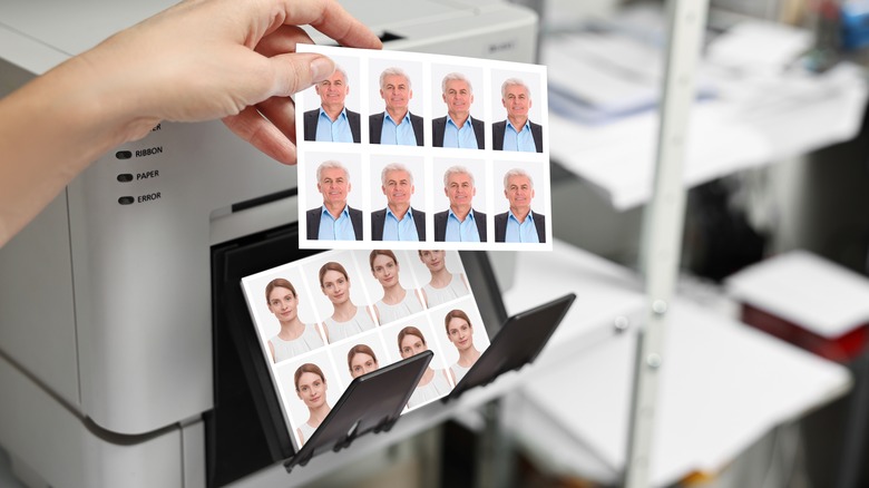 A woman's hand pulling passport photos out of a printer