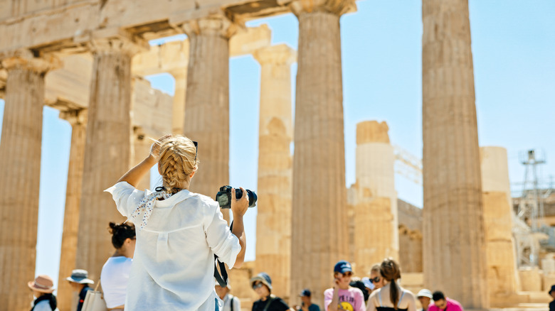 Woman with a camera at the Parthenon in Greece.