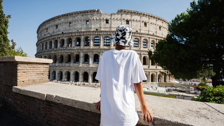 Back of a young tourist looking at the Colosseum