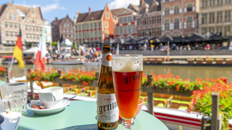 Reddish local beer next to a bottle on a patio overlooking a canal in Bruges, Belgium