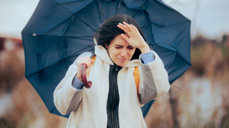 Unhappy woman holding a black umbrella in the wind