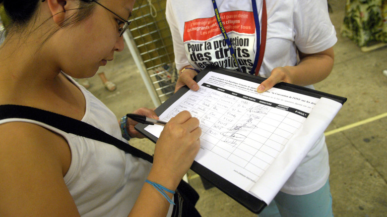 Someone signing a petition in Paris, which may be a scam