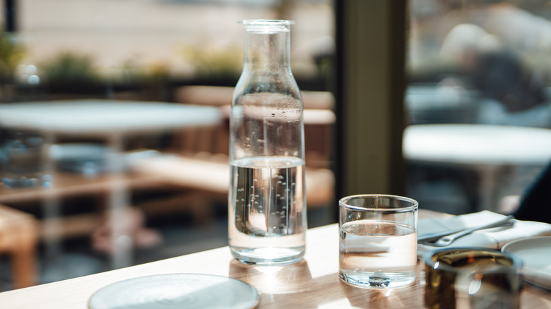 Carafe of water and a glass on a restaurant table.